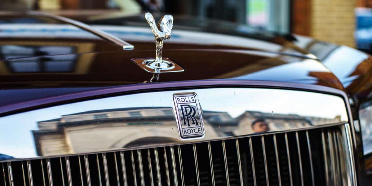 Up close macro shot of the Rolls-Royce emblem on a purple Phantom.