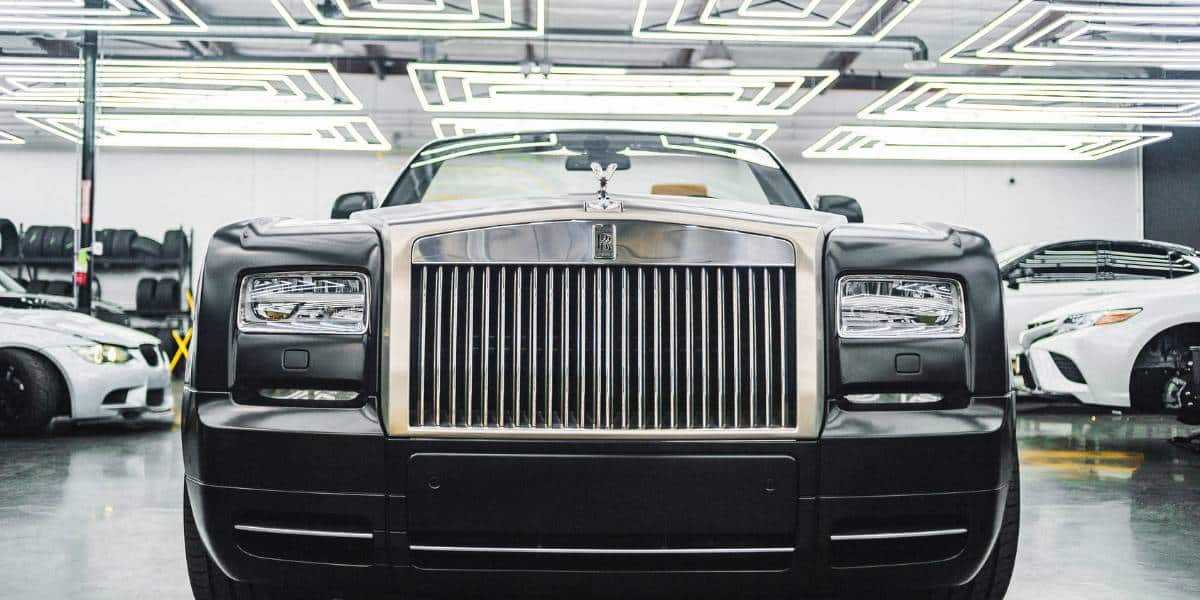 Black 2024 Rolls-Royce in a garage with many other Rolls-Royce vehicles.