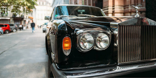 Headlight view of a black old school rolls royce.