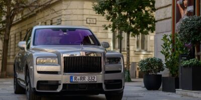 Front view of the 2025 Rolls-Royce Cullinan luxury SUV parked in an urban setting, highlighting its iconic grille and elegant craftsmanship.