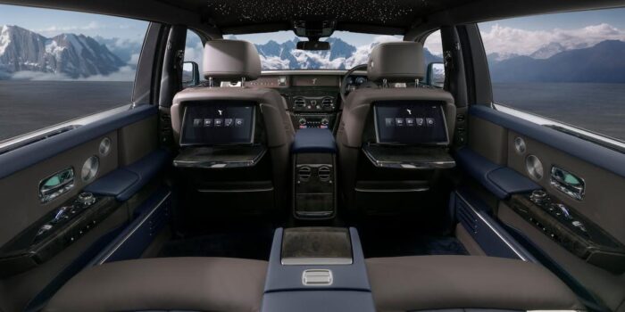 Rear-seat luxury interior of a 2025 Rolls-Royce Phantom showing entertainment screens and starlight headliner, illustrating rolls-royce price value.