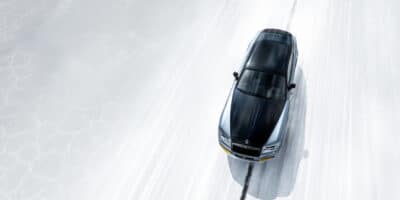 Overhead view of a Rolls-Royce driving on a white road, showcasing the advanced Rolls-Royce suspension system for a smooth and balanced ride