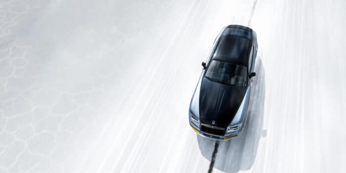 Overhead view of a Rolls-Royce driving on a white road, showcasing the advanced Rolls-Royce suspension system for a smooth and balanced ride