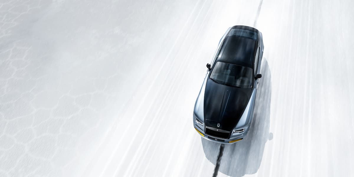 Overhead view of a Rolls-Royce driving on a white road, showcasing the advanced Rolls-Royce suspension system for a smooth and balanced ride