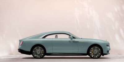 Side view of the Rolls-Royce Spectre electric luxury coupe in duck egg blue with elegant fastback design.