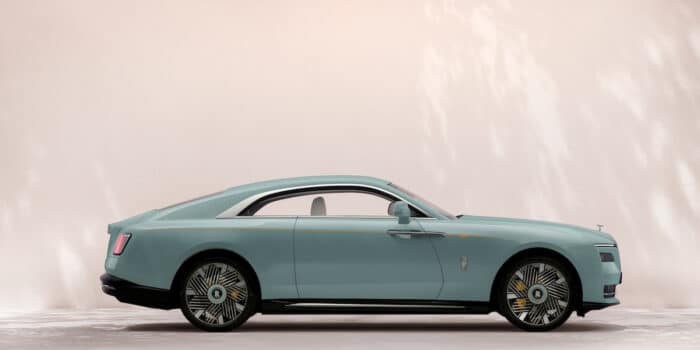 Side view of the Rolls-Royce Spectre electric luxury coupe in duck egg blue with elegant fastback design.