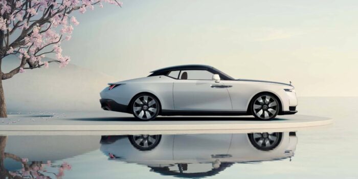 Side view of a luxury car beside a reflective pool representing Rolls Royce coachbuild craftsmanship and exclusivity.