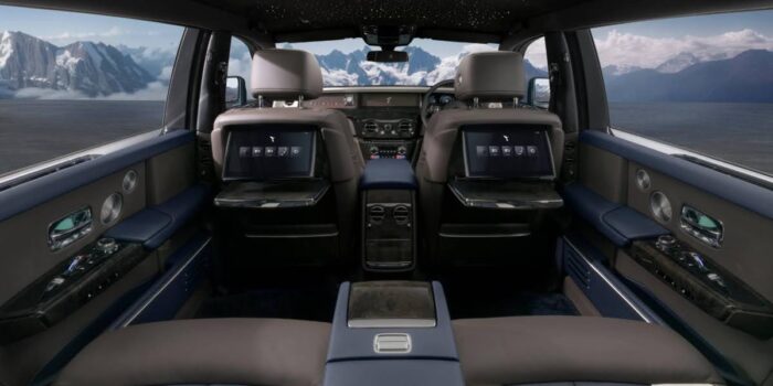 Luxurious Rolls Royce interior showcasing premium leather seats, starlight headliner, and rear seat screens in an elegant cabin setting.